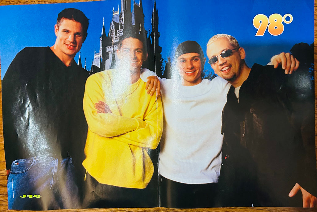 J-14 magazine double-sided poster side A featuring all four members of 98 Degrees posing in front of Cinderella Castle at Disney Magic Kingdom wearing casual outfits, 98 degrees in gold bubble font top right, J-14 logo bottom left, blue sky background