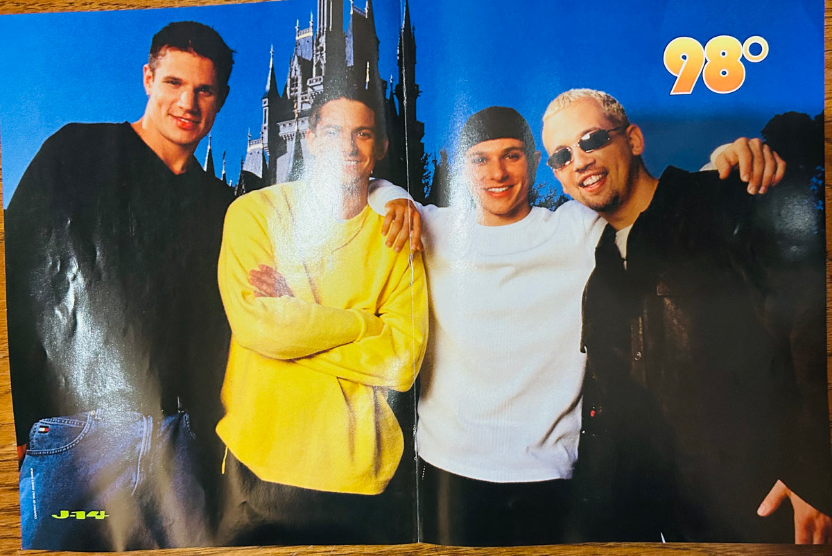 J-14 magazine double-sided poster side A featuring all four members of 98 Degrees posing in front of Cinderella Castle at Disney Magic Kingdom wearing casual outfits, 98 degrees in gold bubble font top right, J-14 logo bottom left, blue sky background
