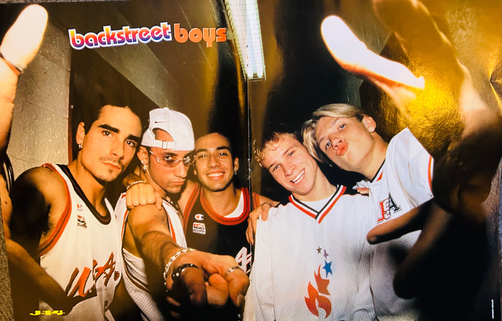 J-14 magazine double-sided poster side A featuring all five Backstreet Boys backstage in USA basketball jerseys with Champion and flame graphics fists out under dramatic stage lighting, backstreet boys in rainbow bubble font top left, J-14 logo bottom left