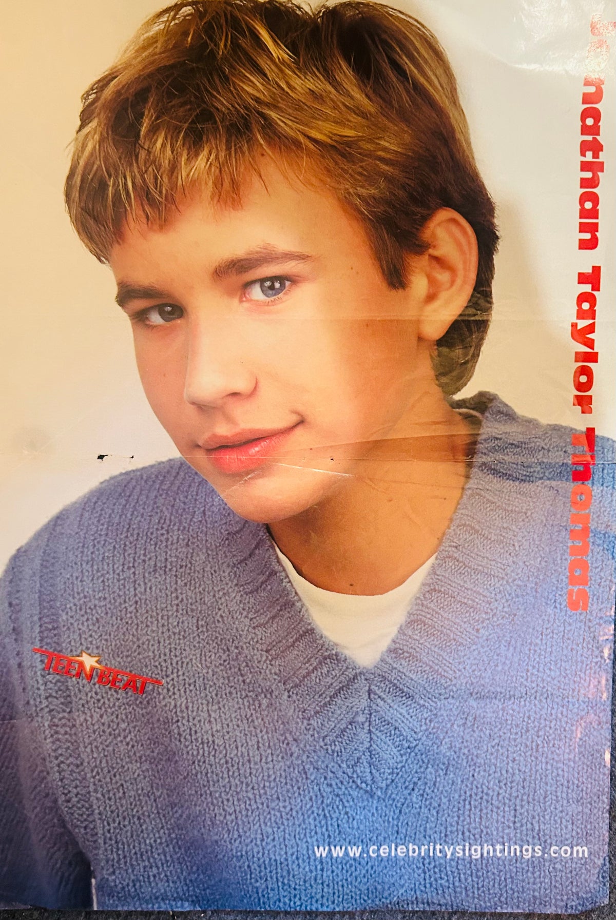 Teen Beat magazine double-sided poster side A featuring Jonathan Taylor Thomas JTT close-up portrait in blue V-neck sweater over white tee with tousled highlighted hair and soft smile, nathan Taylor Thomas in red vertical font right side, Teen Beat logo bottom left, www.celebritysightings.com bottom right