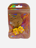 Pair of yellow kawaii teddy bear clay charm drop earrings with pink bow ties on silver fish hook wires, sealed in holographic zip bag with New Fashion cat display card