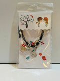 Two matching black braided cord bracelets with red, white, and black beads and rhinestone flower charms, sealed in packaging with illustrated couple display card