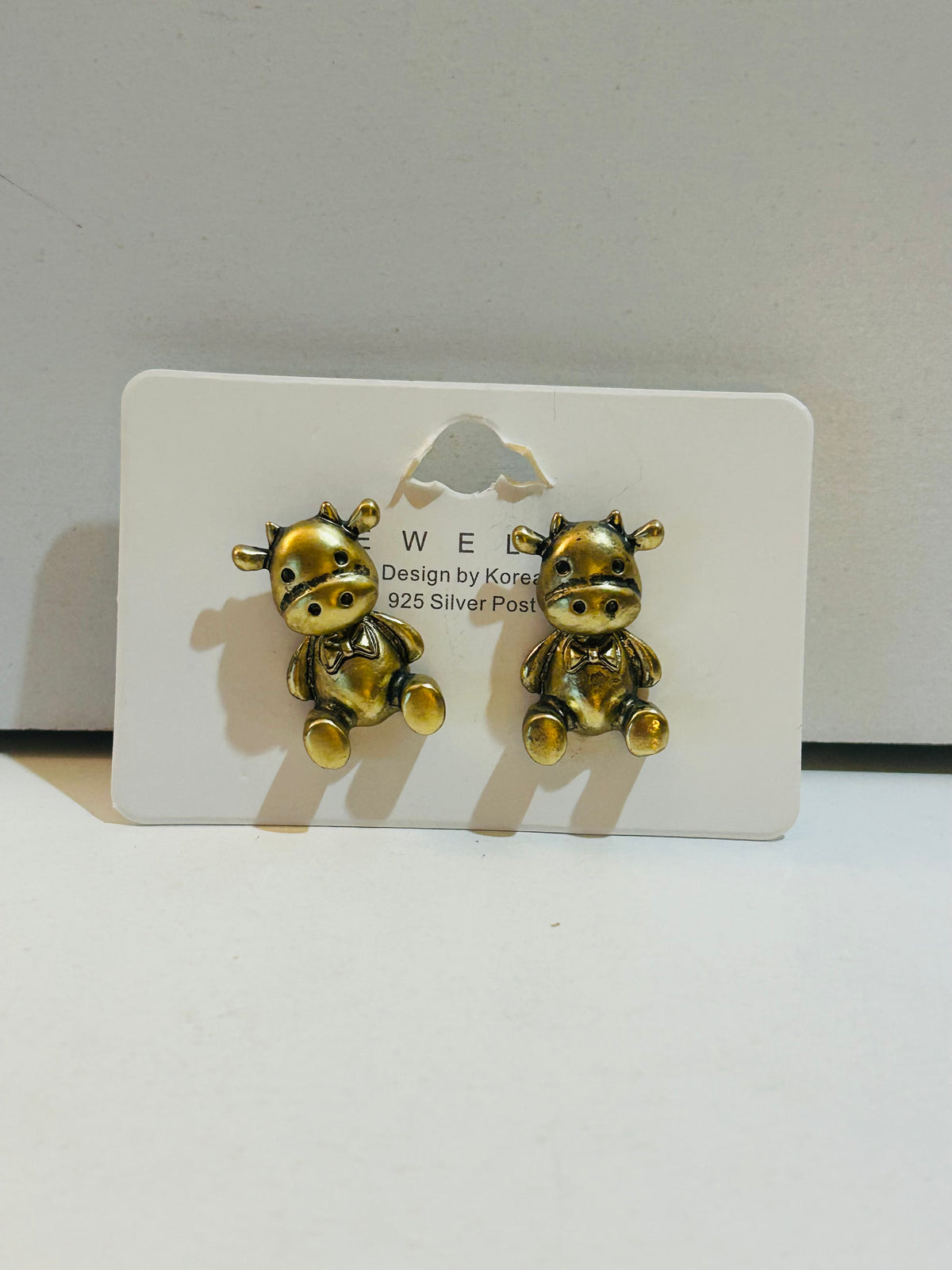 Pair of antique gold-tone seated cow character stud earrings with 925 silver posts on display card, Korean design