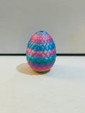 2 inch rainbow pastel dragon scale egg in pink, blue, purple, and teal with small loop hole at top, contains surprise mini owl figure inside