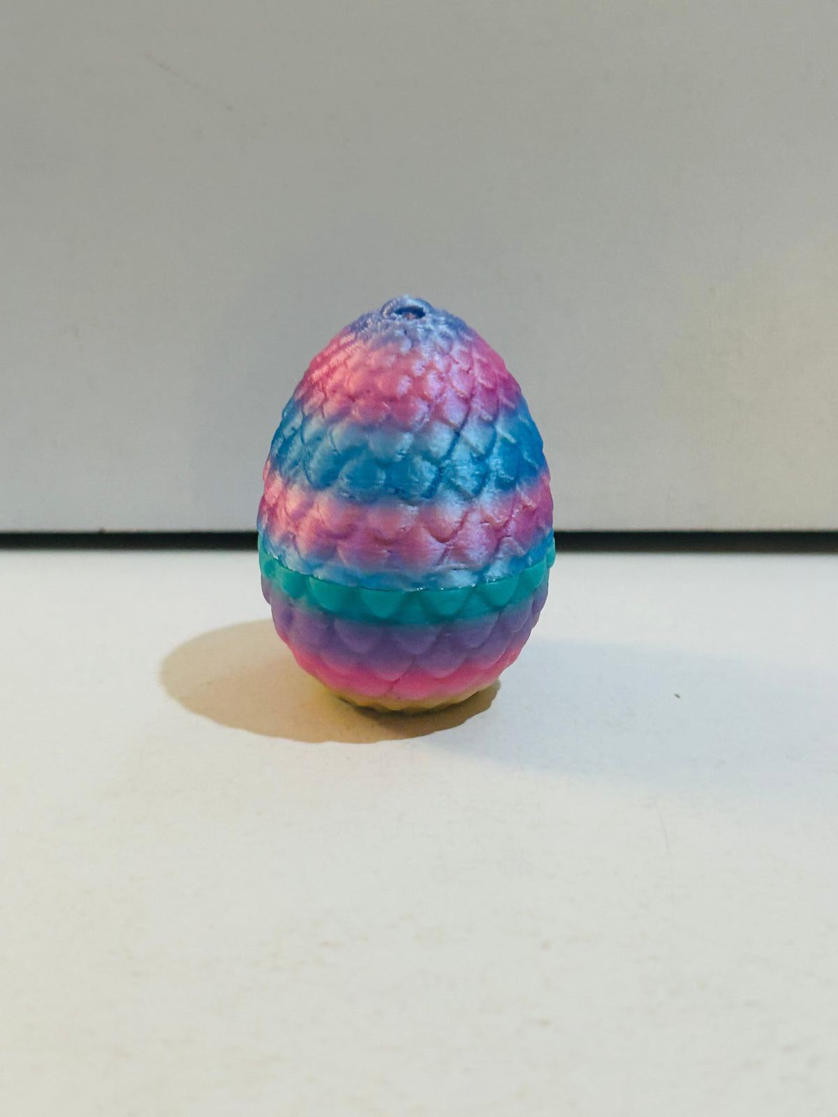 2 inch rainbow pastel dragon scale egg in pink, blue, purple, and teal with small loop hole at top, contains surprise mini owl figure inside