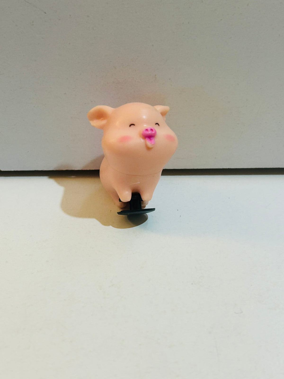 1.5 inch kawaii chubby pink pig figurine with rosy cheeks, pink snout, happy expression, and small black suction cup base