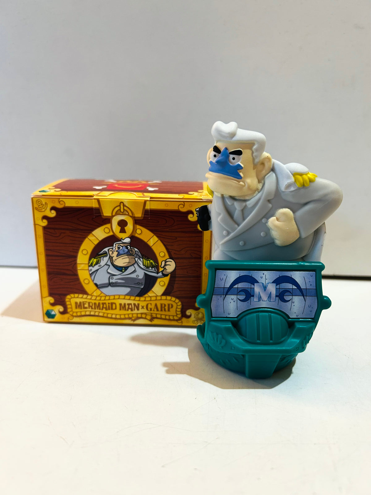 Mermaid Man x Garp collectible figure on a teal base beside its matching box