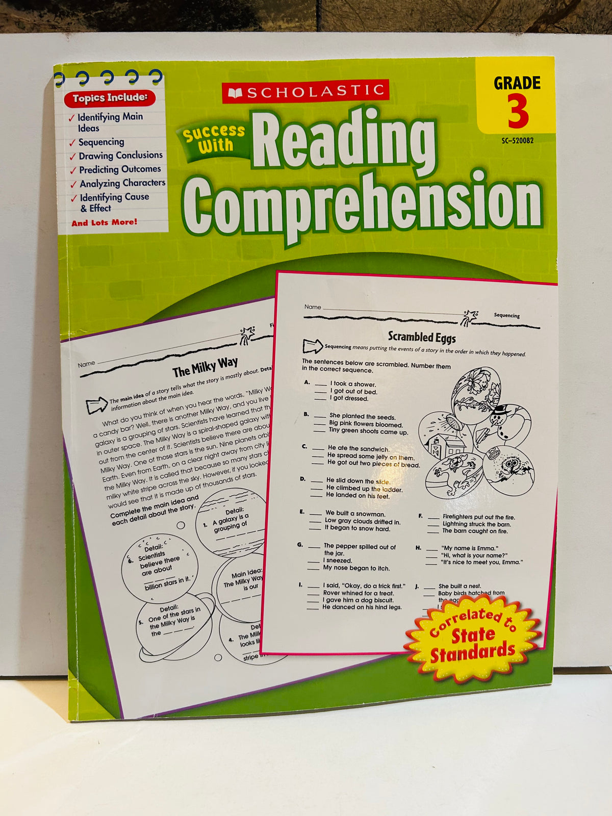 Scholastic Success With Reading Comprehension Grade 3 spiral-bound workbook cover, green and yellow design, correlated to State Standards, with sample worksheet pages fanned out in front