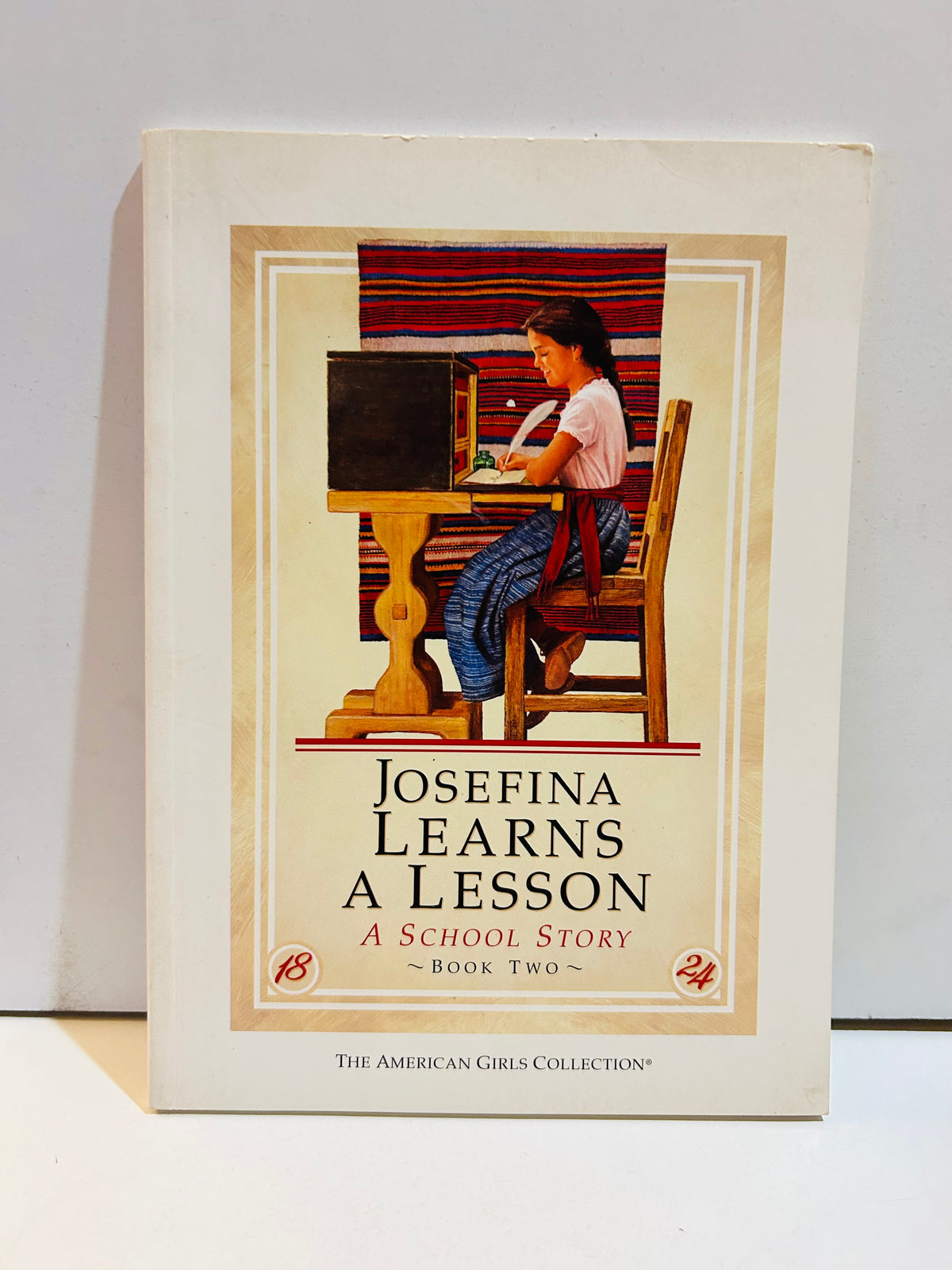 Josefina Learns a Lesson A School Story Book Two cover from The American Girls Collection featuring Josefina writing at a wooden desk with colorful woven textile backdrop, set in 1824, Pleasant Company 1997
