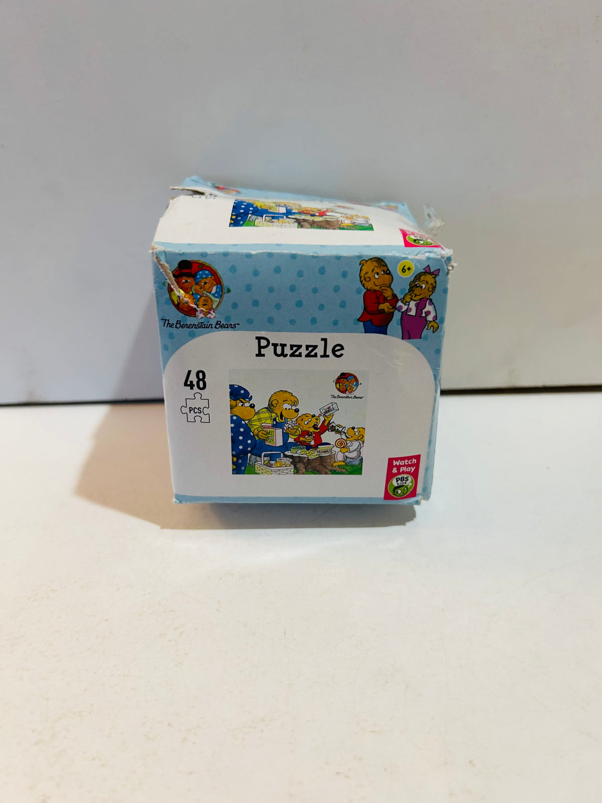 The Berenstain Bears 48-piece puzzle box in light blue with polka dots, showing 48 pcs puzzle with Berenstain Bears family kitchen dining scene image, PBS Kids Watch and Play logo, ages 6 plus, box shows exterior wear