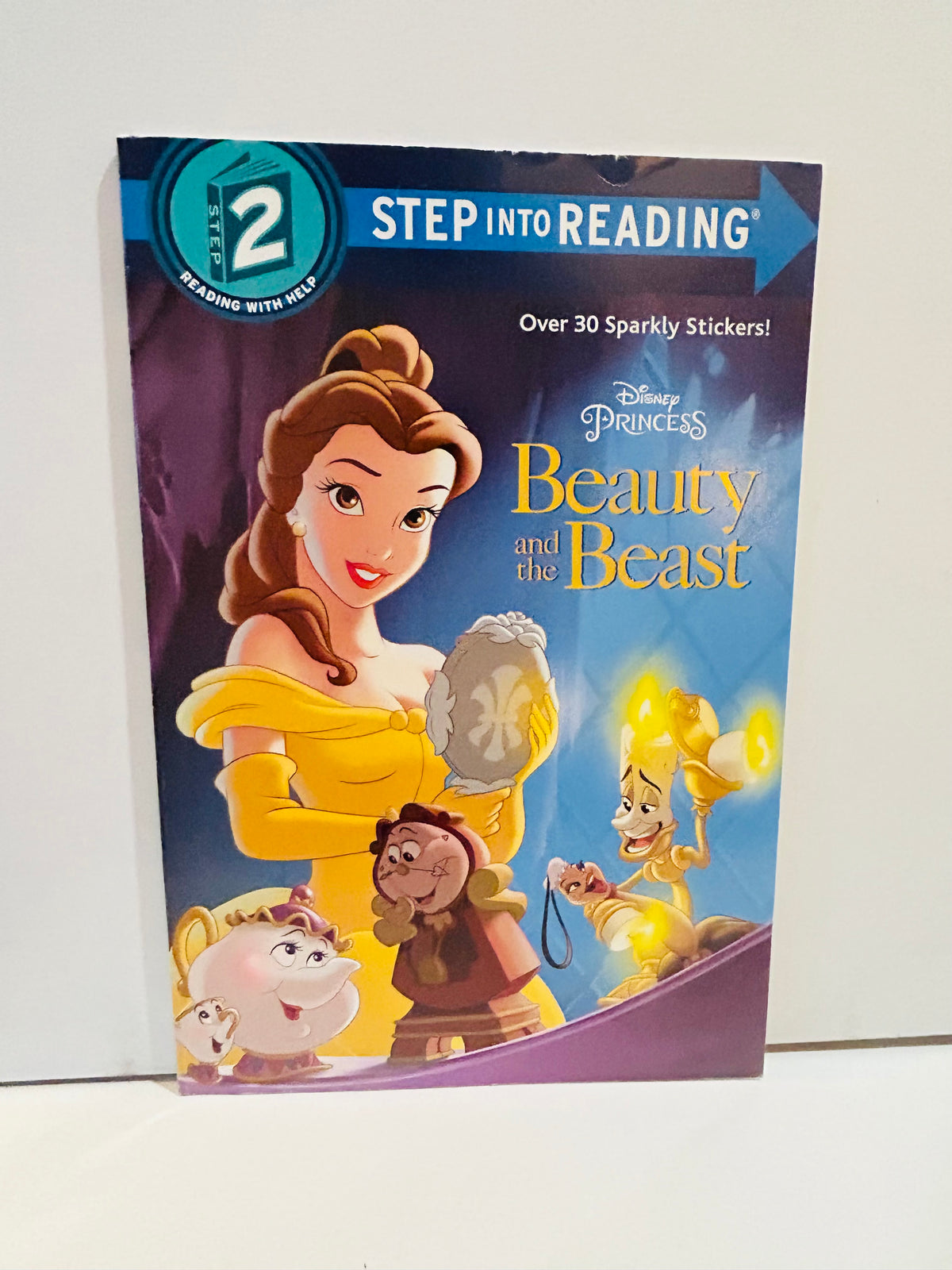 Disney Princess Beauty and the Beast Step Into Reading Step 2 2017 paperback cover featuring Belle in yellow gown holding enchanted mirror with Mrs Potts Chip Cogsworth and Lumiere, Over 30 Sparkly Stickers callout