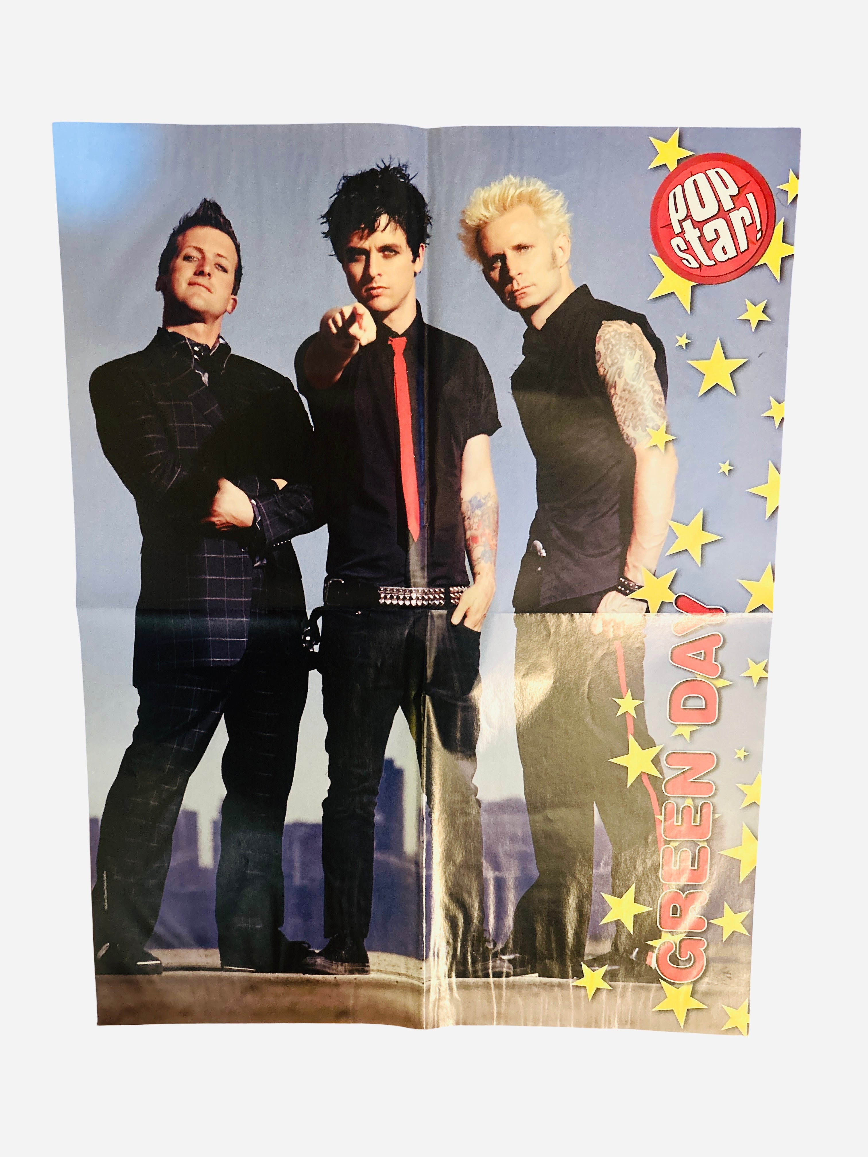 Green Day Pop Star! Magazine poster - back side featuring Billie Joe Armstrong, Tre Cool and Mike Dirnt standing against a city skyline on blue star background