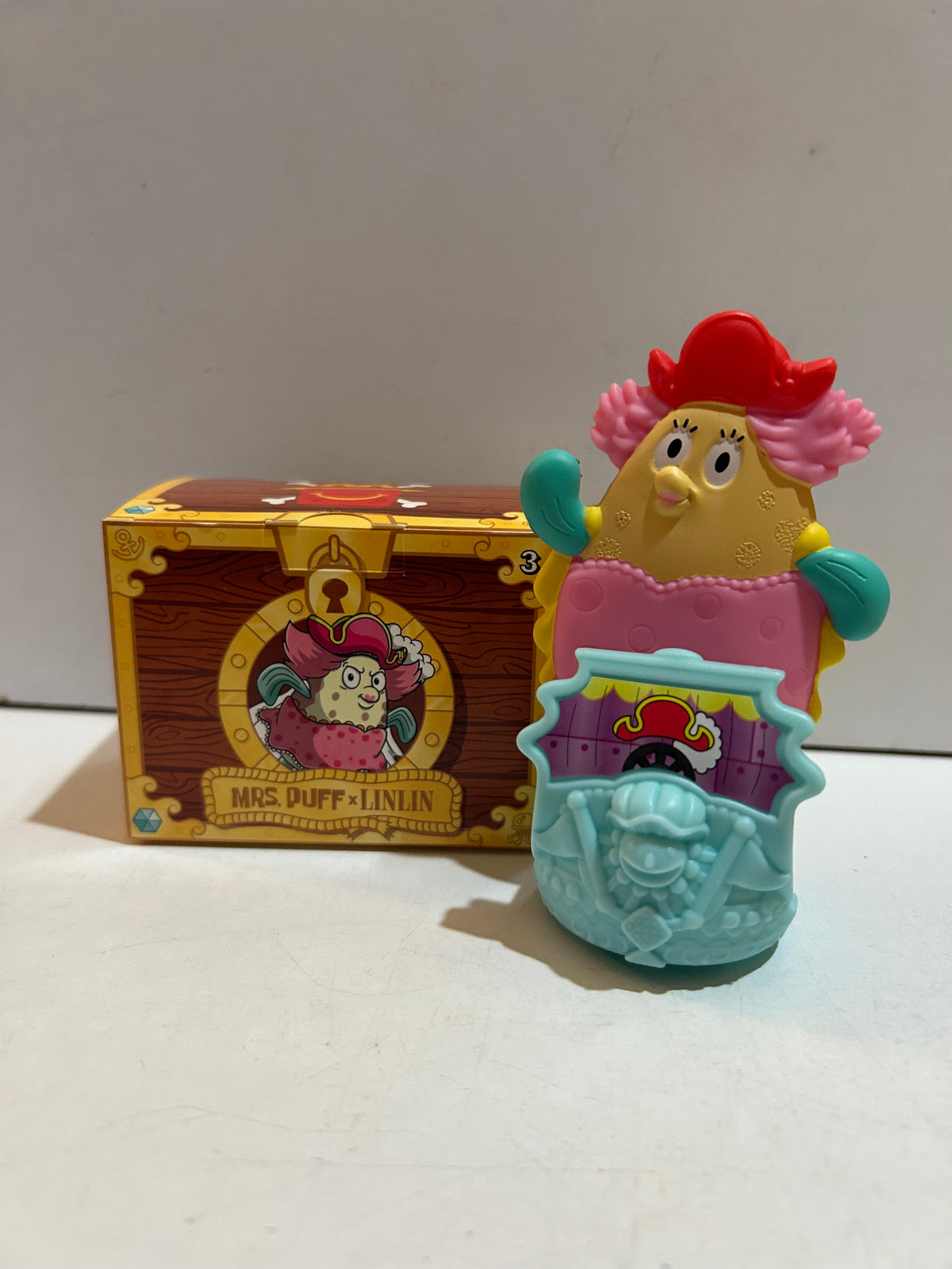 Mrs. Puff x Linlin figure with pink outfit and red pirate hat on a light blue themed base beside its box