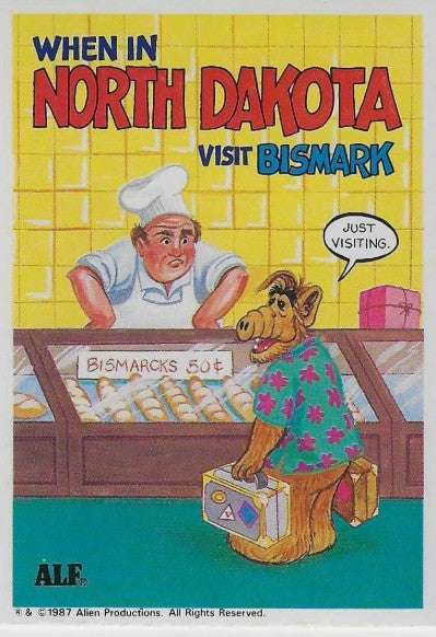 U.S. of ALF North Dakota sticker featuring ALF with suitcase at bakery counter full of Bismarcks doughnuts saying just visiting to suspicious baker
